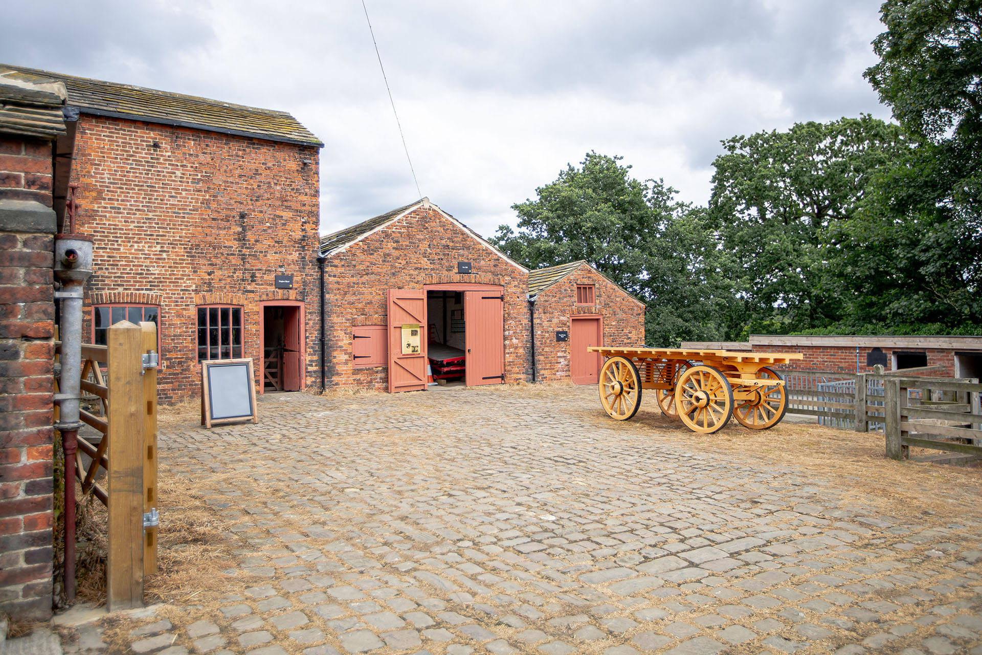 The courtyard to Temple Newsam Farm showing the cobblestone floor, old machine and well maintained barns and buildings