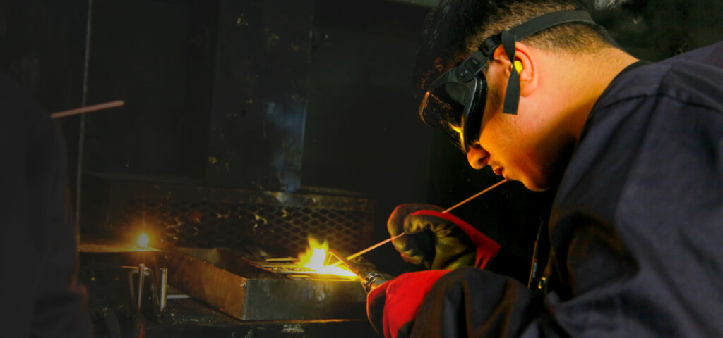 Student wearing protective gear while doing welding