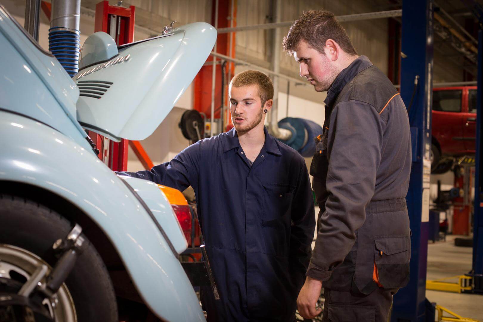Auto motive tutor showing a student the engine of a car