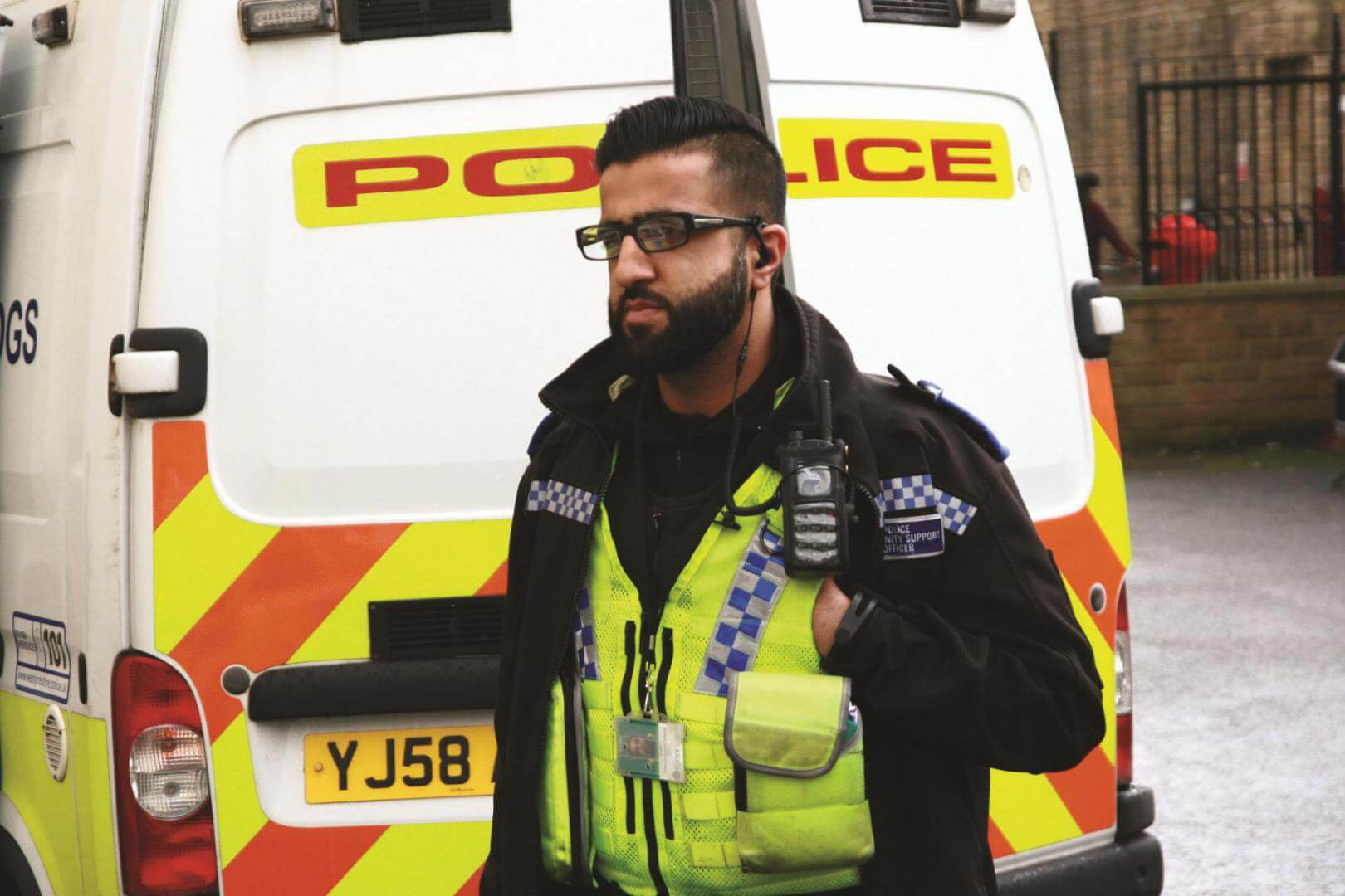 Policeman dressed in full uniform in front of a police van