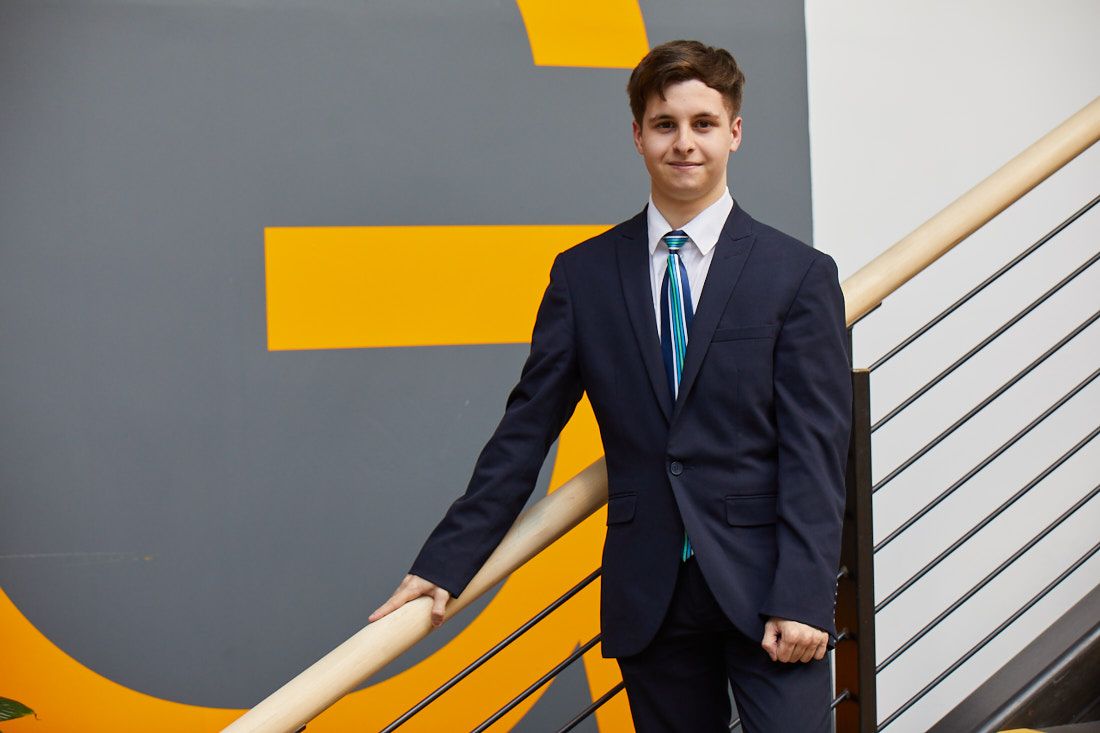 Travel and Tourism student in a suit and tie standing on steps
