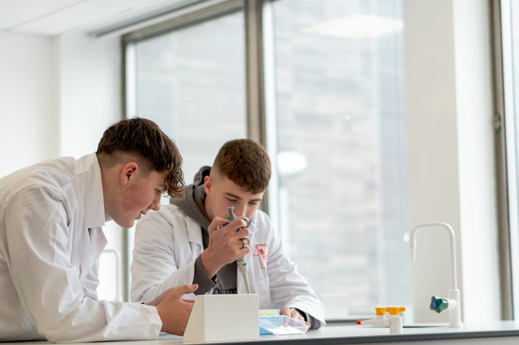 Two LCC Applied Science students working on an experiment putting chemicals in to test tubes