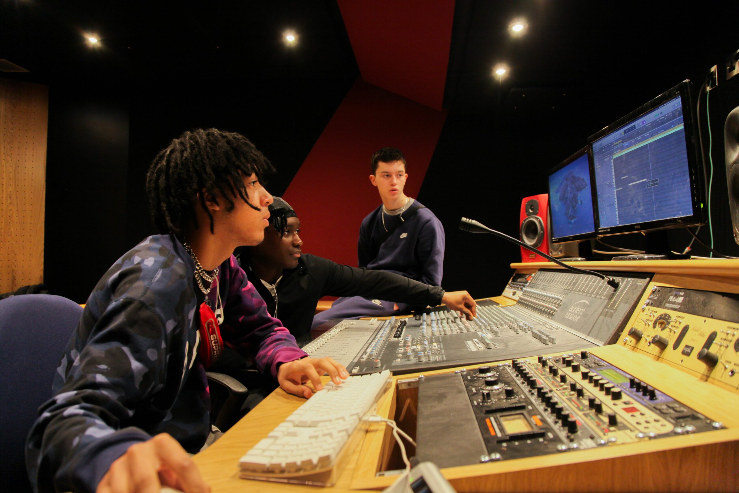Students producing music in the production room, mixing the levels