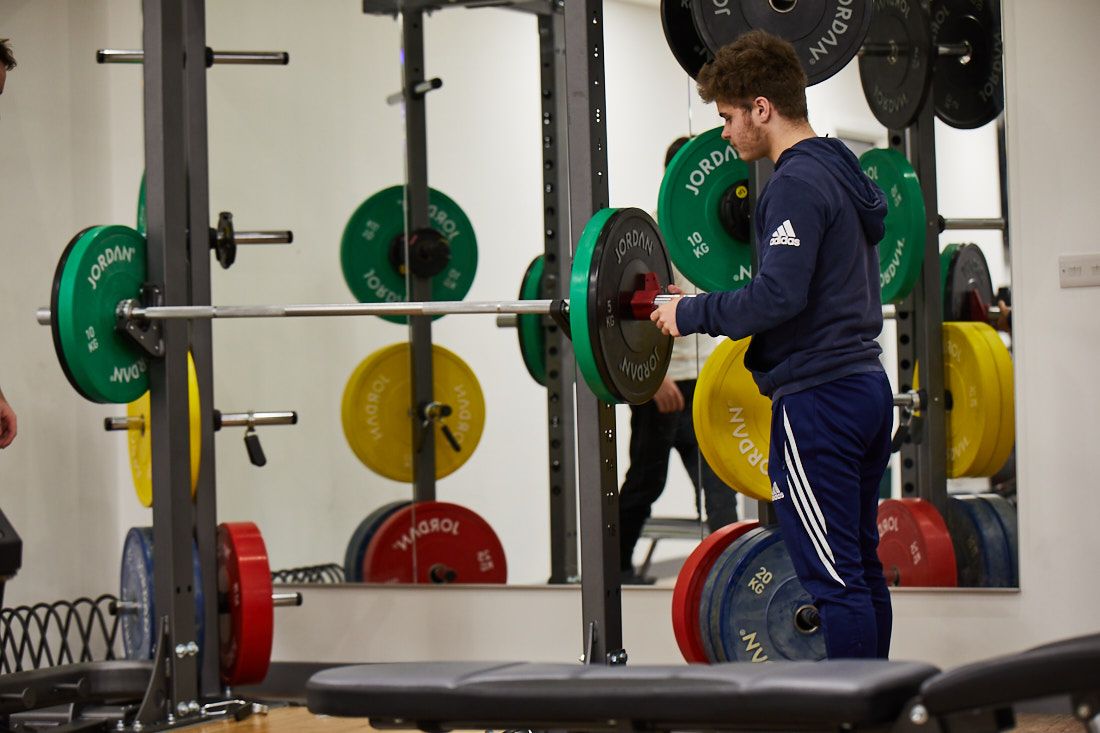 Student adding plates to a squat rack
