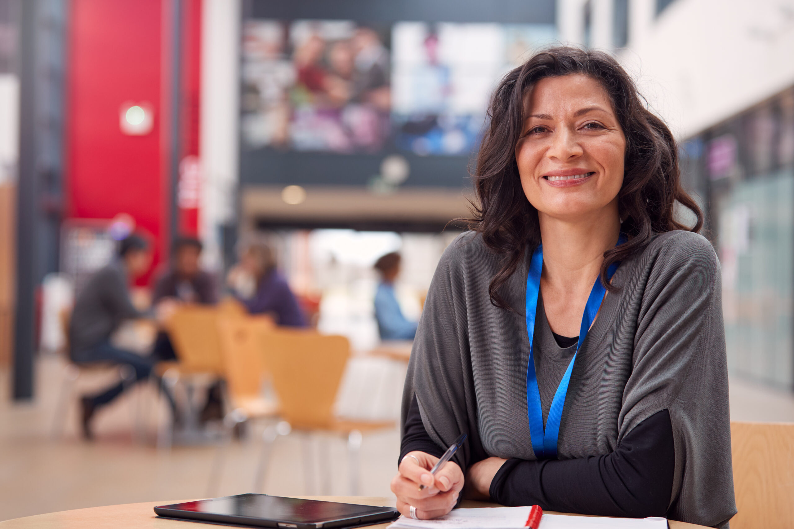 Adult student smiling holding a pen sitting with iPad and notes in learning centre