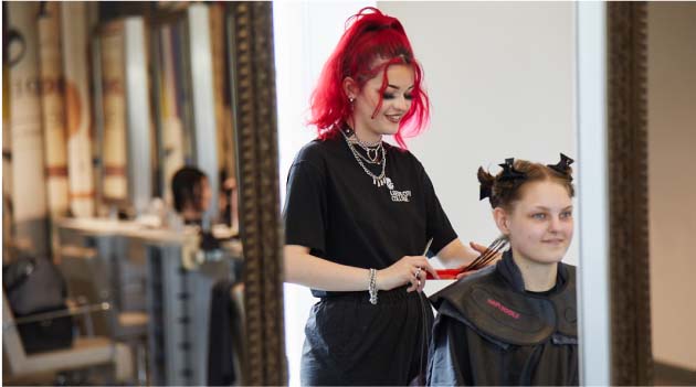 Hairdresser apprentice in hair studio doing a wet hair cut