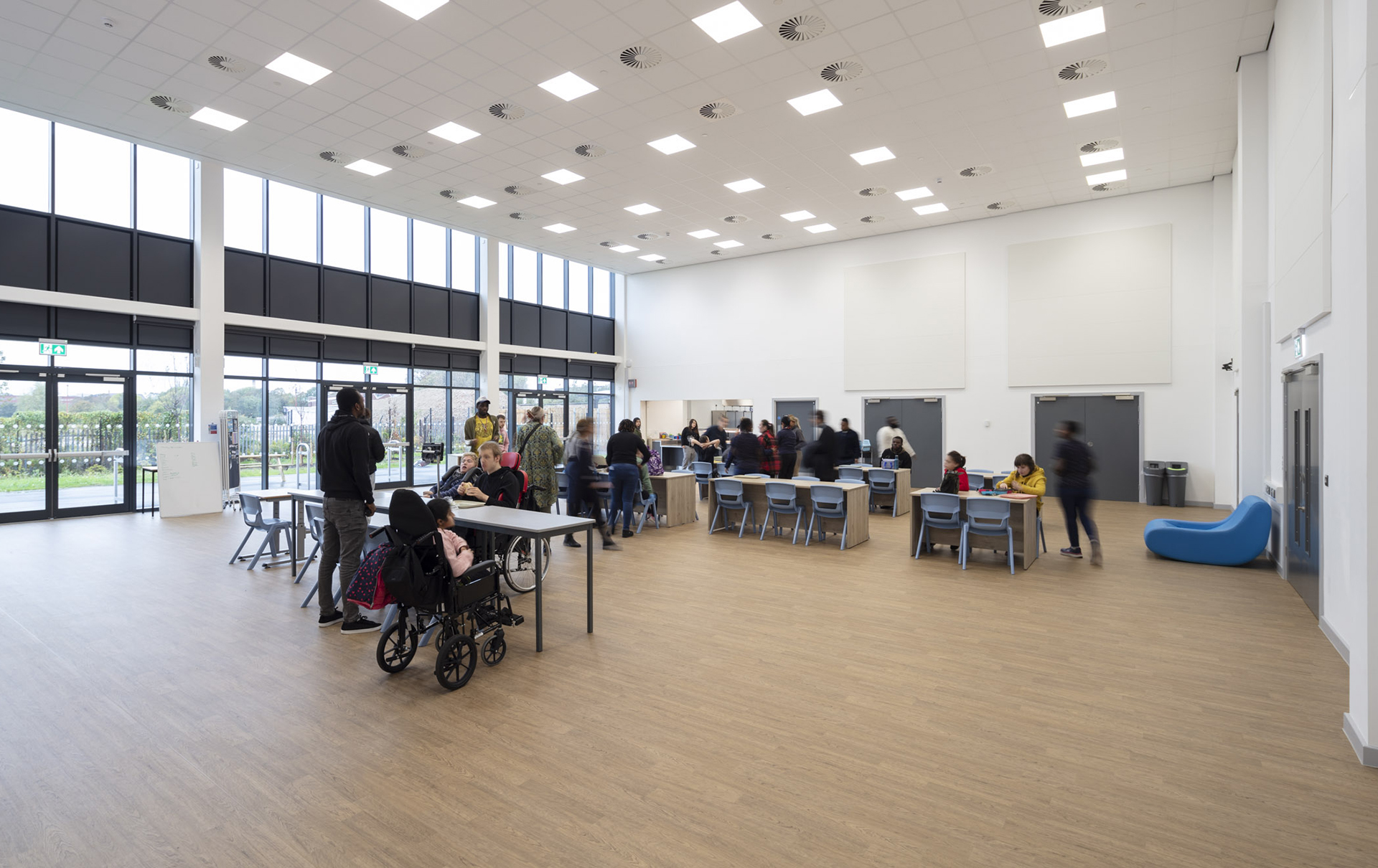 Students are gathering in the open-plan canteen with desks and chairs