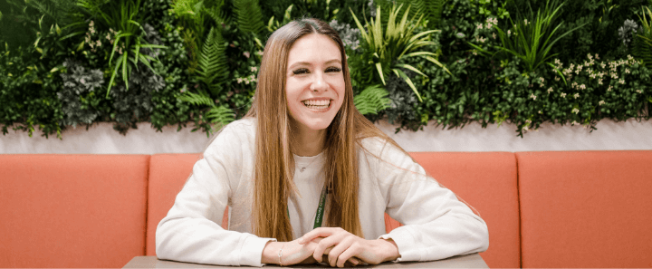 Student in cream jumper sit down in cafe smiling happily