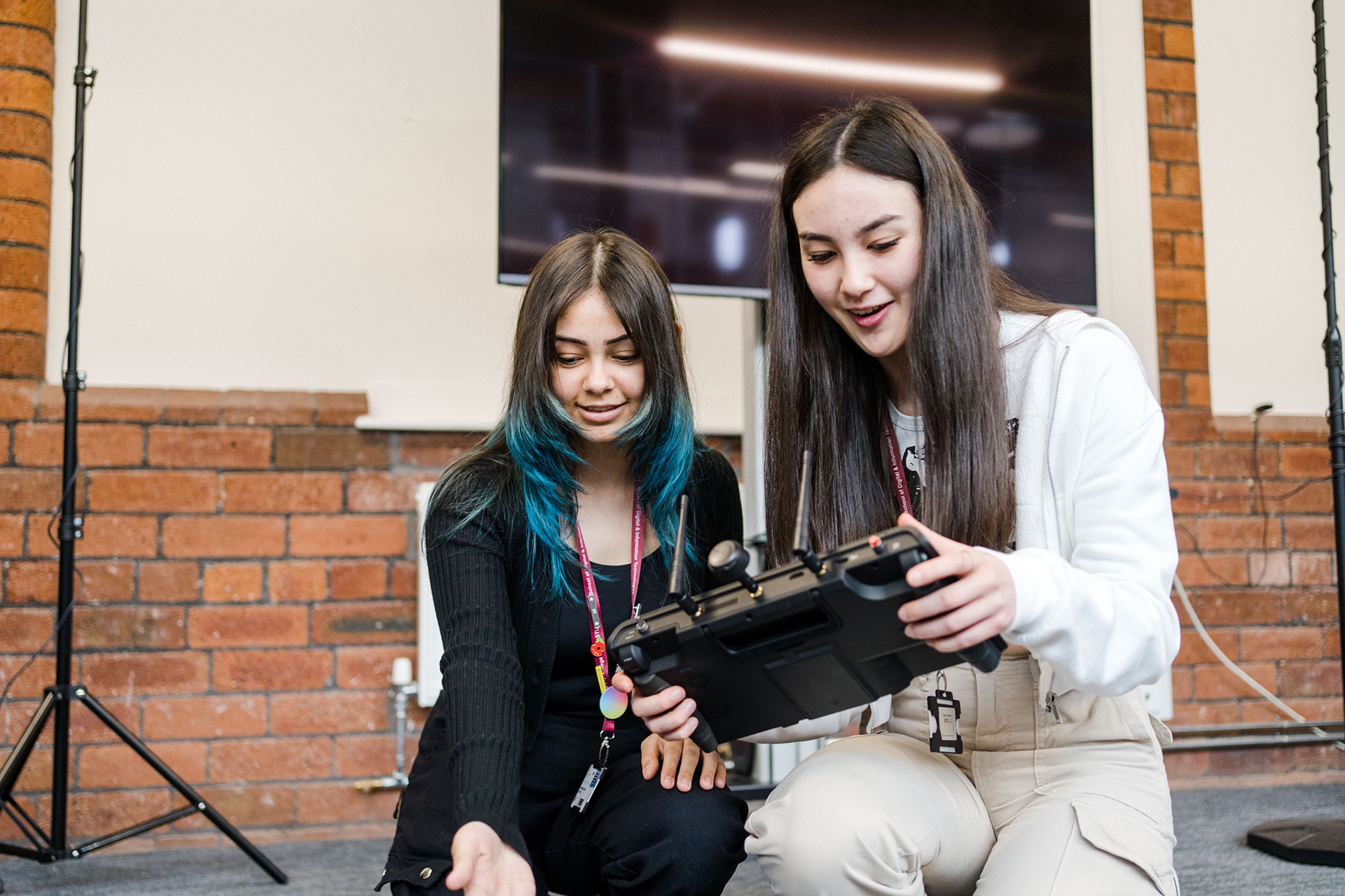 Two students looking at a controller device in studio classroom