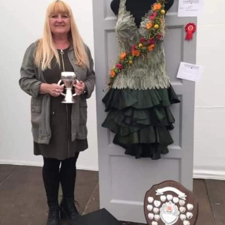 Teacher Julie standing with her prize for winning a florist competition