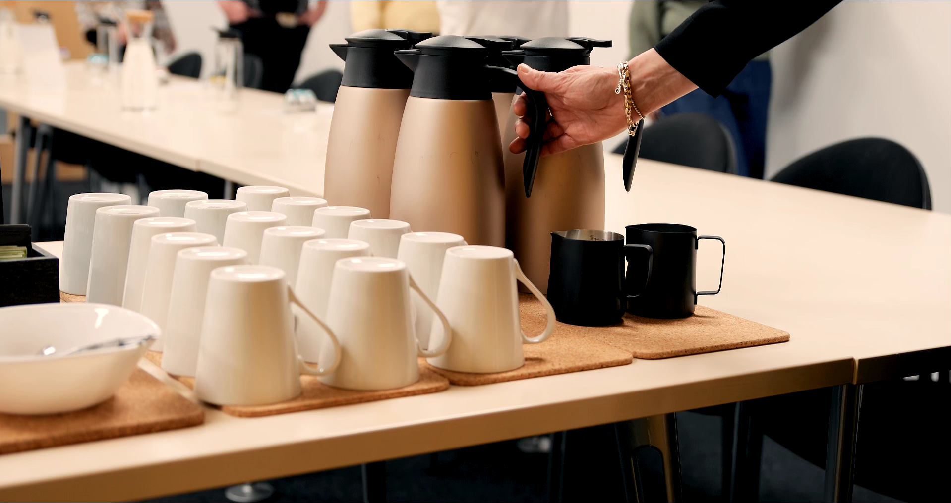 Display of white ceramic mugs and stainless steel flasks on table