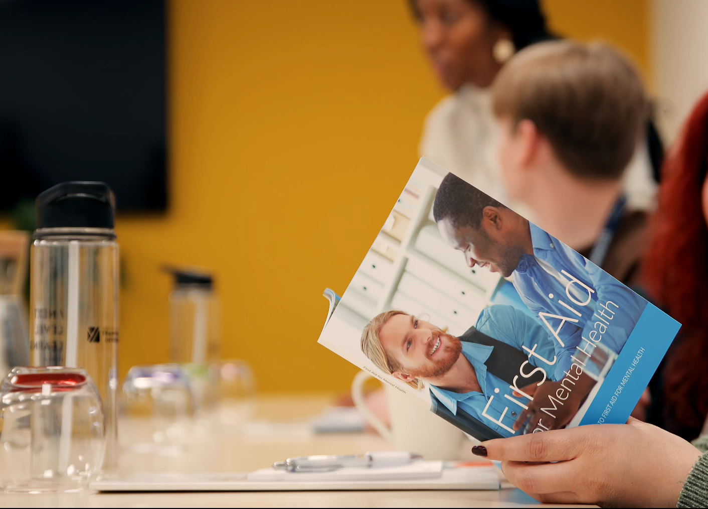 Group of learners reading first aid brochure in meeting room