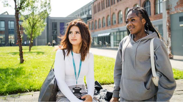 Two students stood smiling in the sunshine outside of the Leeds City College Printworks campus