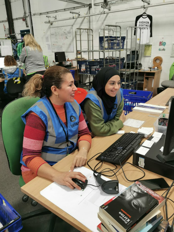 An adult student and a member of staff sitting at and using a computer together.