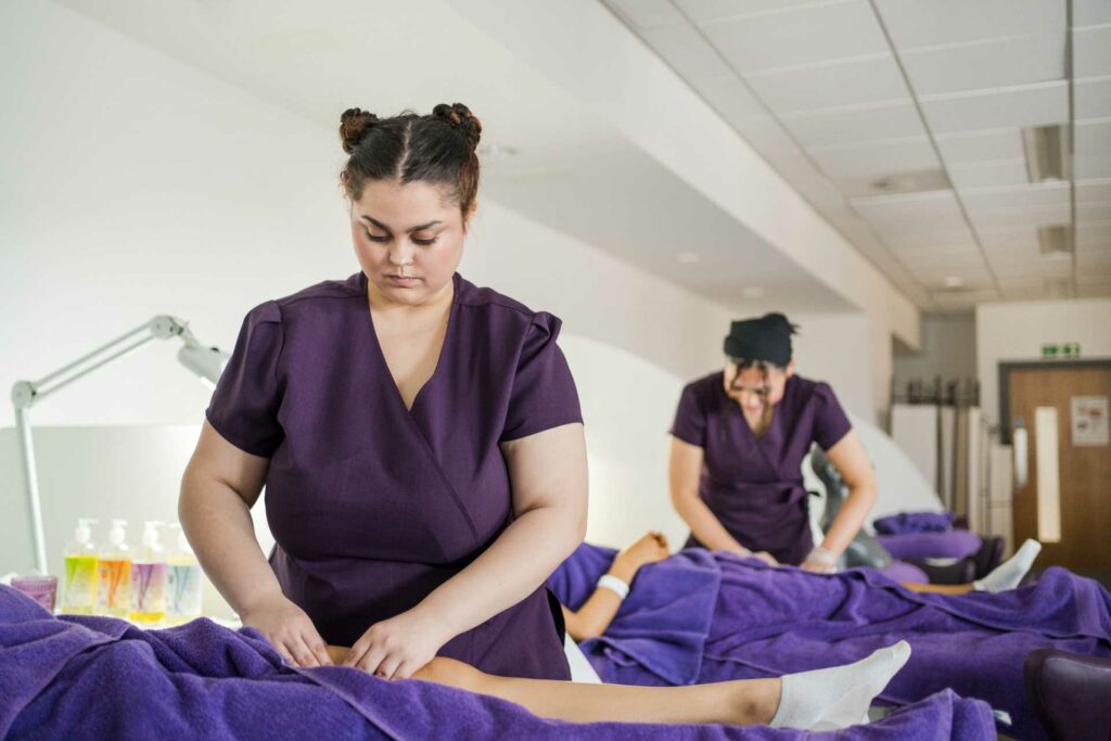 Two female hair and beauty students are giving a massage treatment to clients