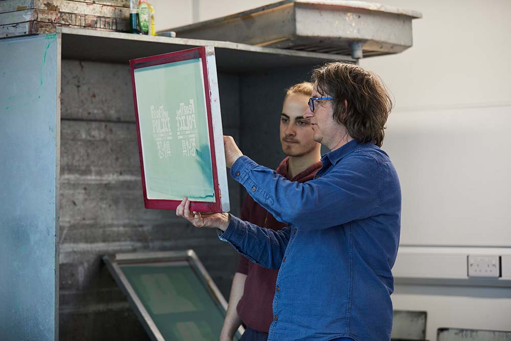 Creative Arts teacher looking at a screen print with an Art and Design student