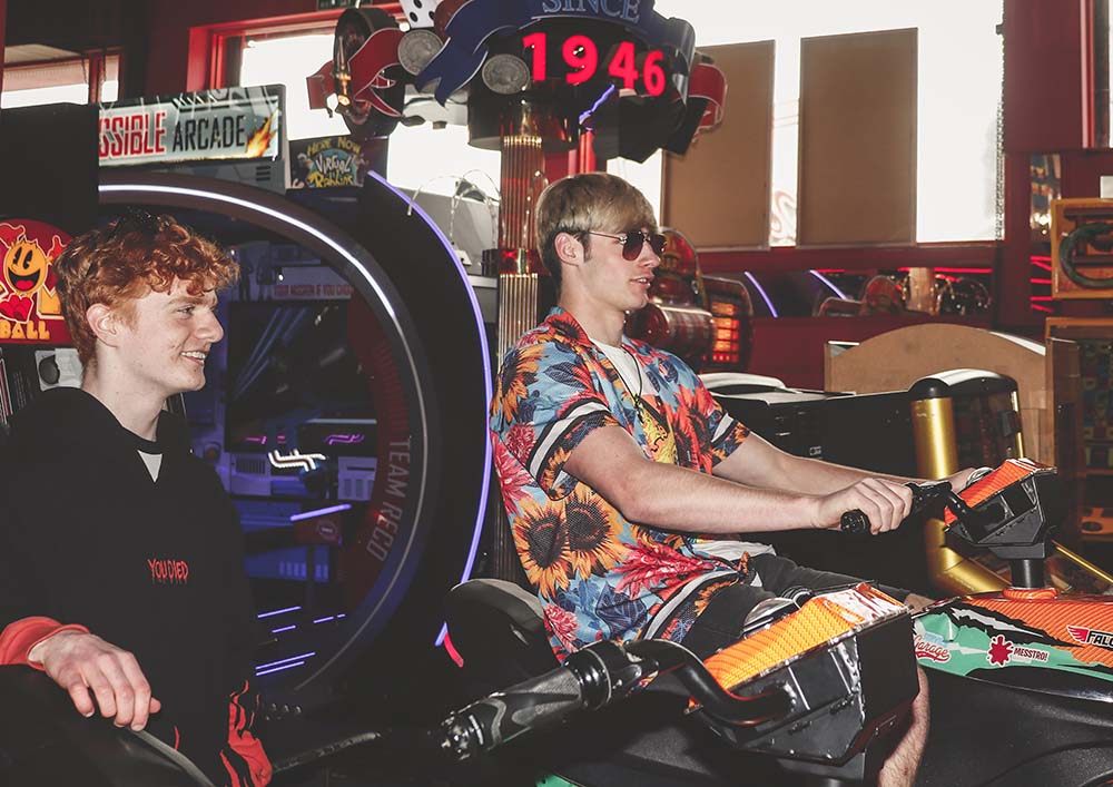 Photography by Creative Arts student Keira Bathgate showing two people having fun in the arcades section of a diner, one wearing sunglasses and a hawaiian shirt