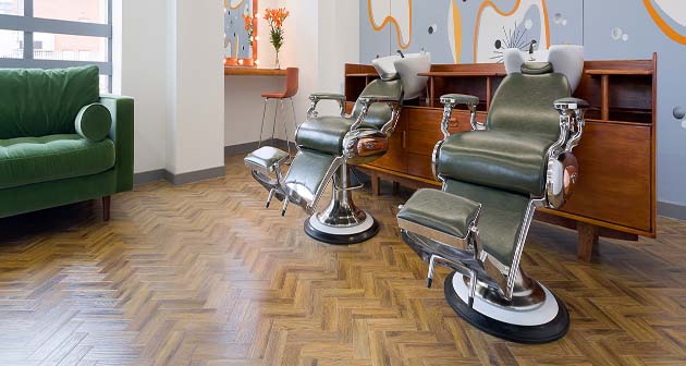 Hairdressing chairs by sinks and green velvet sofa ready for customers in the Printworks salon