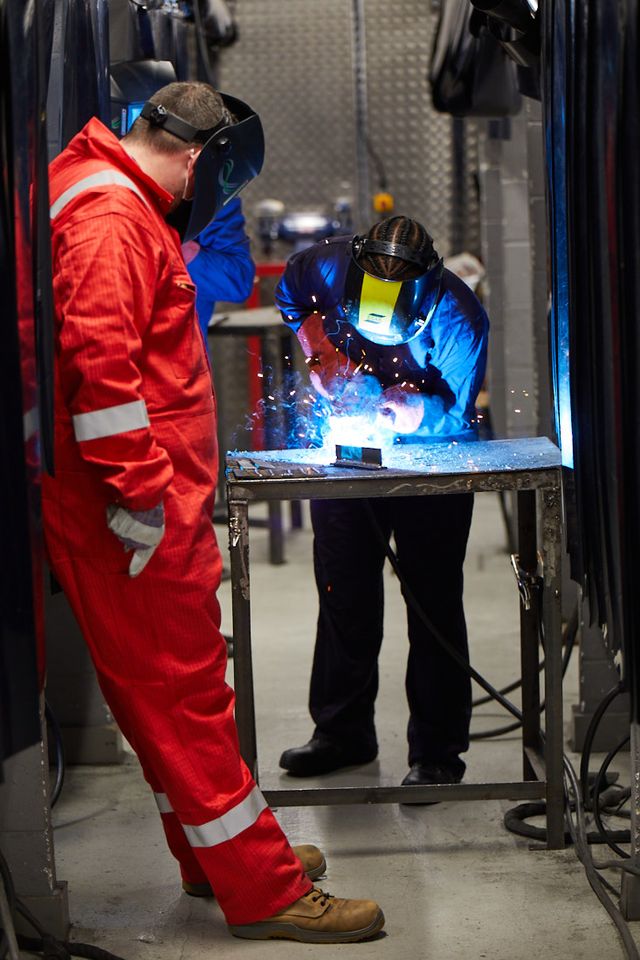 Two students wearing protective gear welding in the workshop