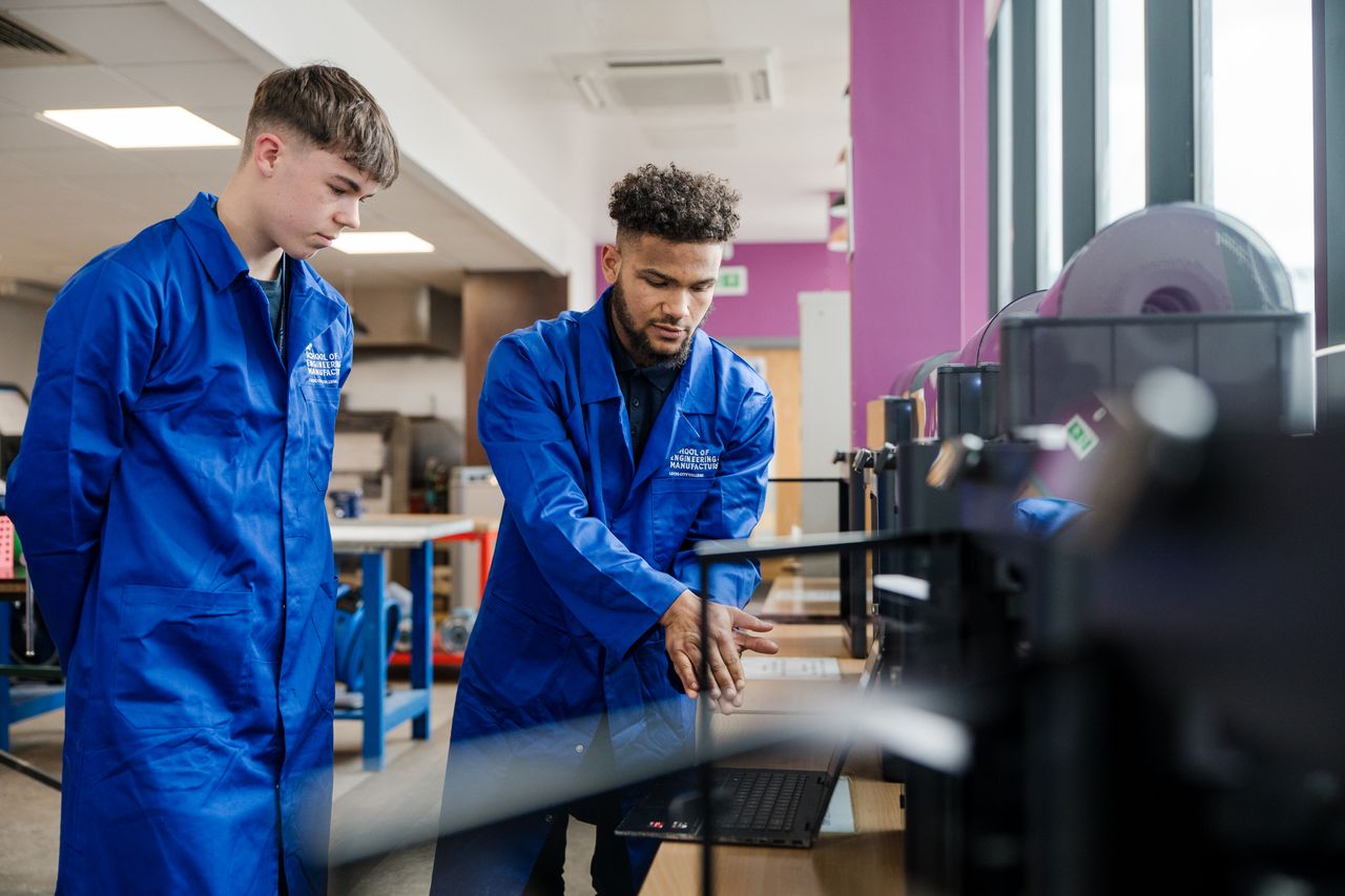 Two students going through the 3d printers looking of they need refilling and any maintenance