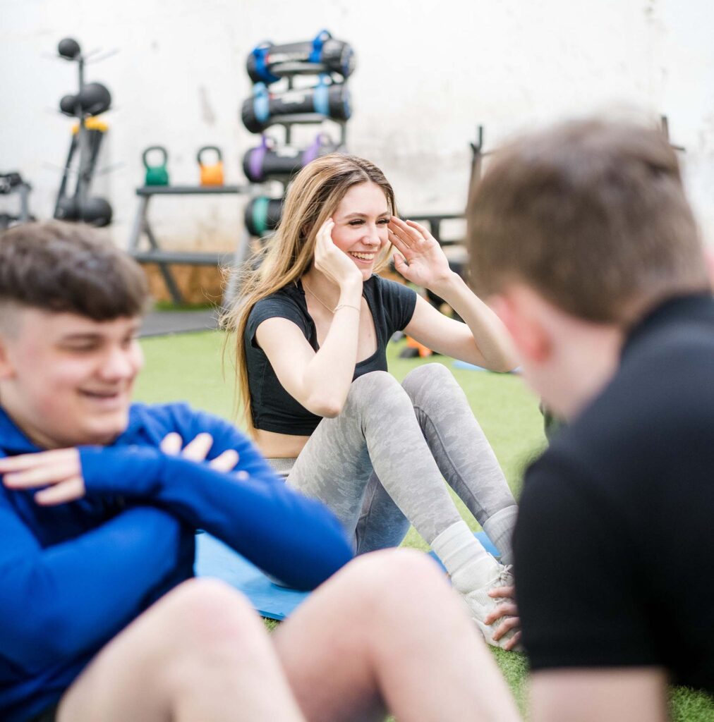 Students smiling in the gym doing sit-up