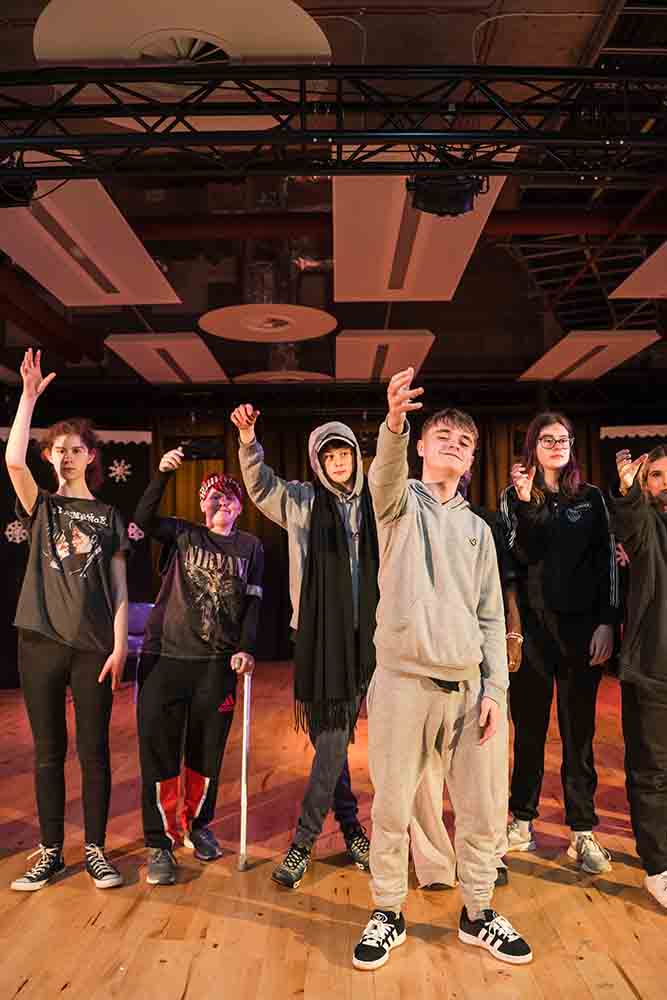 Students standing with one hand lifted in dance studio