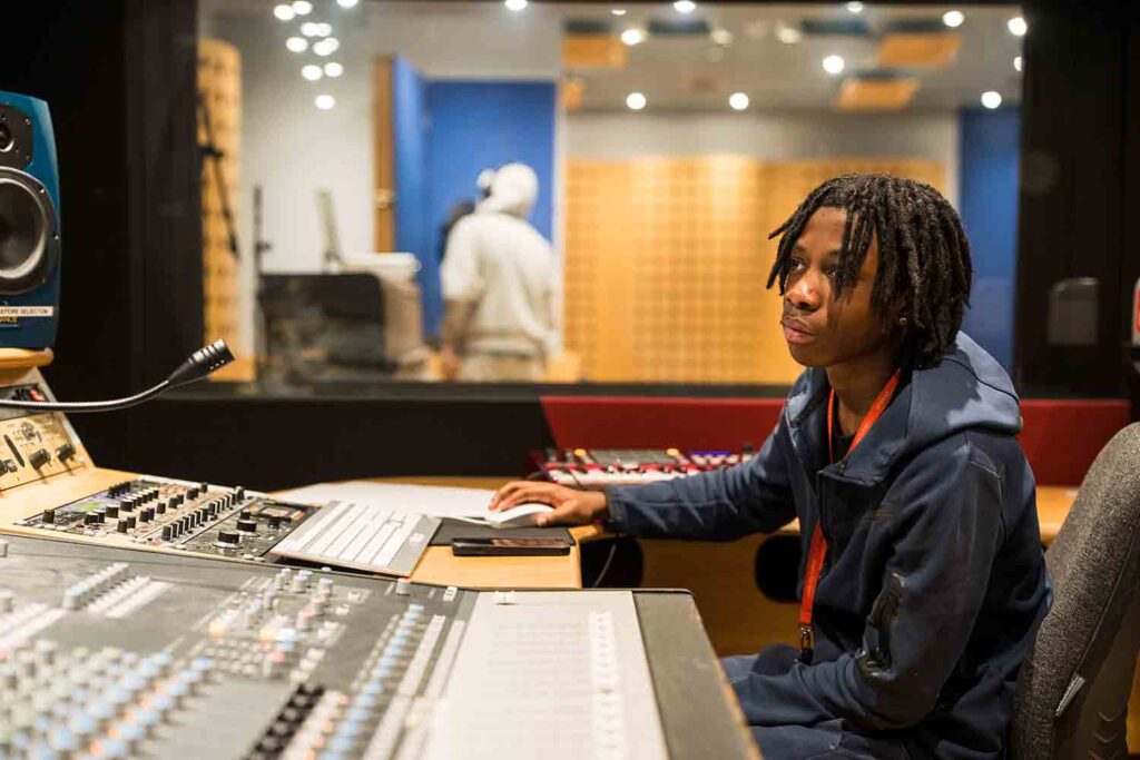 Student working on sound mixing console in the audio studio