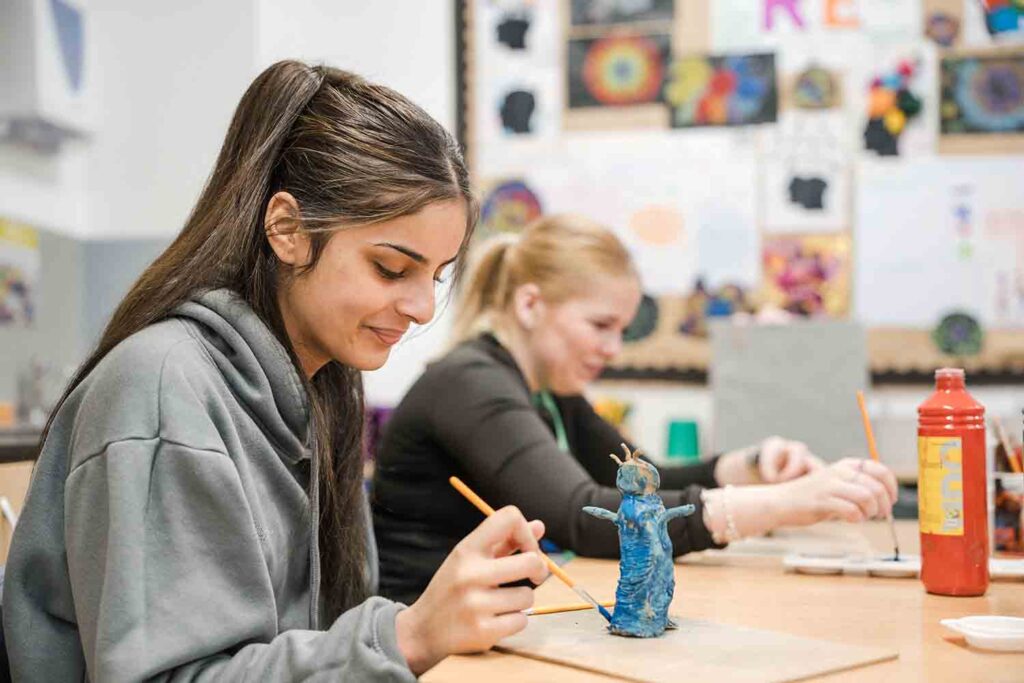 Students painting artwork using watercolour in classroom