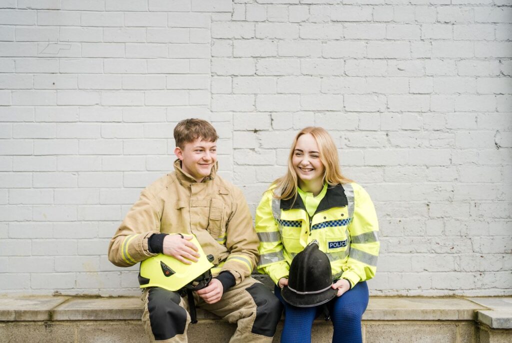 Two students one male and one female wearing police and firefighting uniform