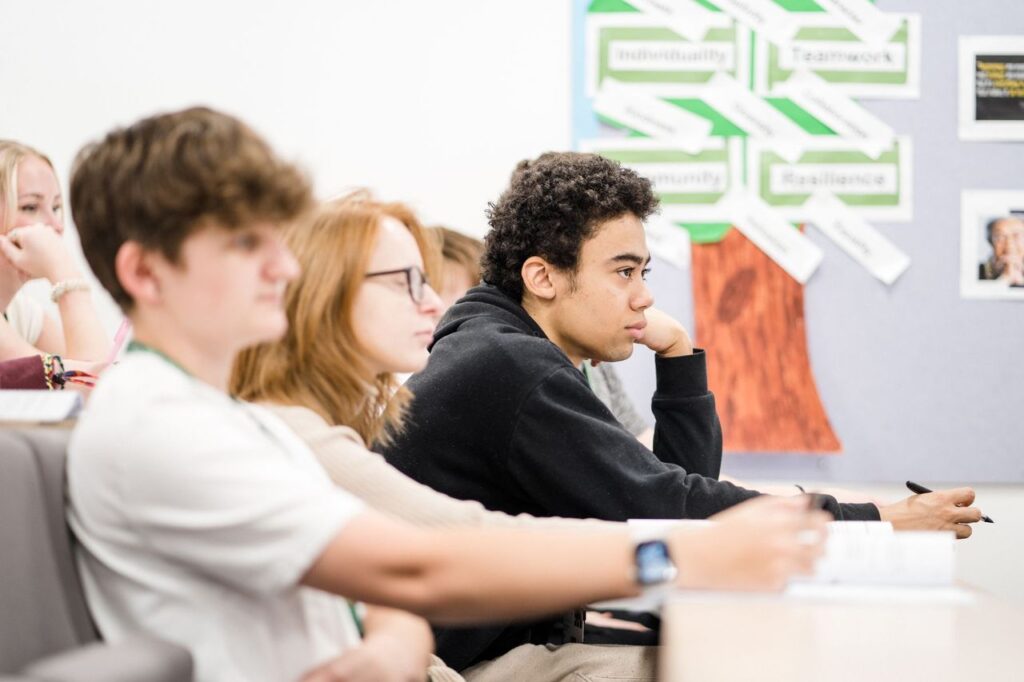 Classroom of students looking to the front of the class listening to the tutor
