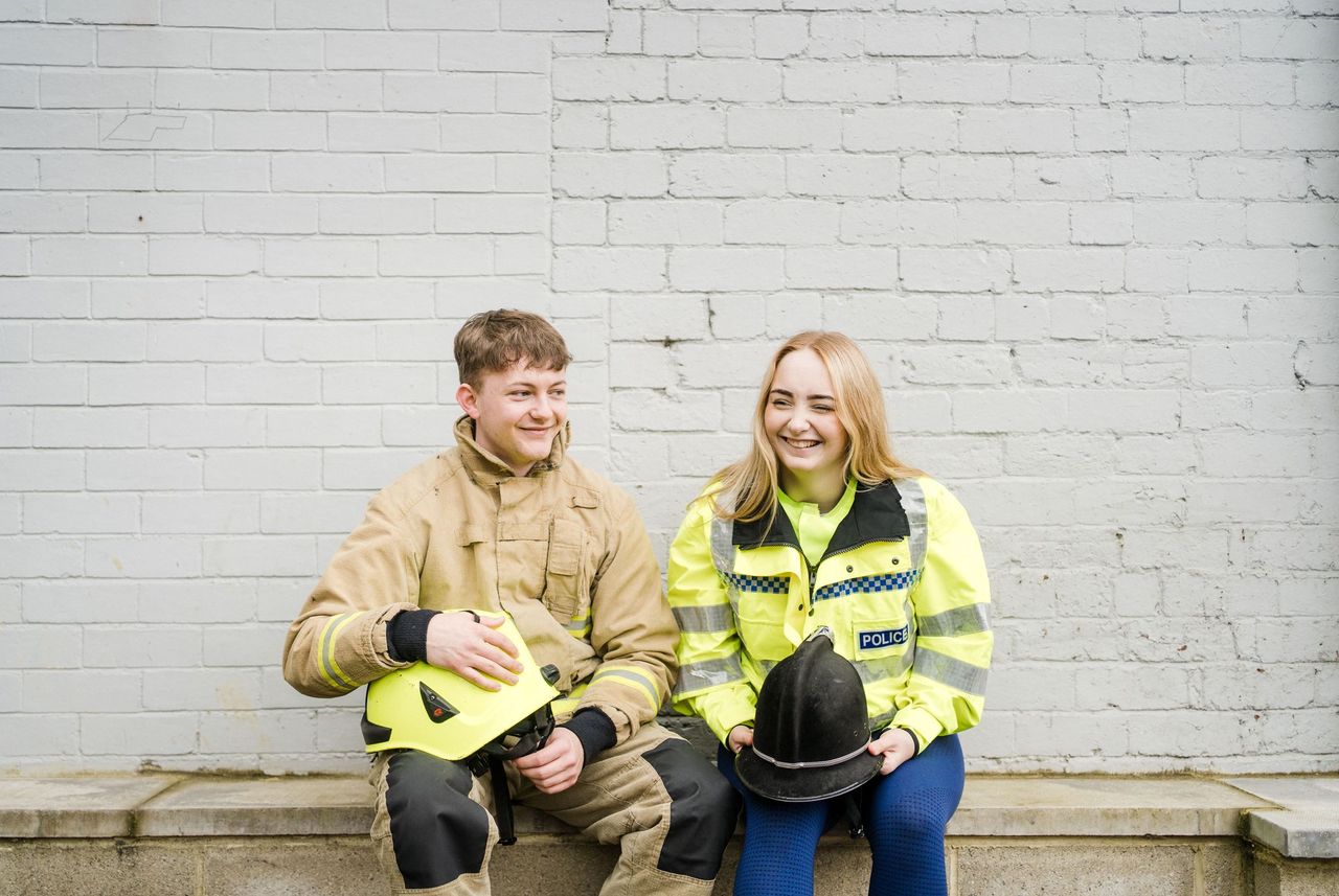 Two students one male and one female wearing police and firefighting uniform