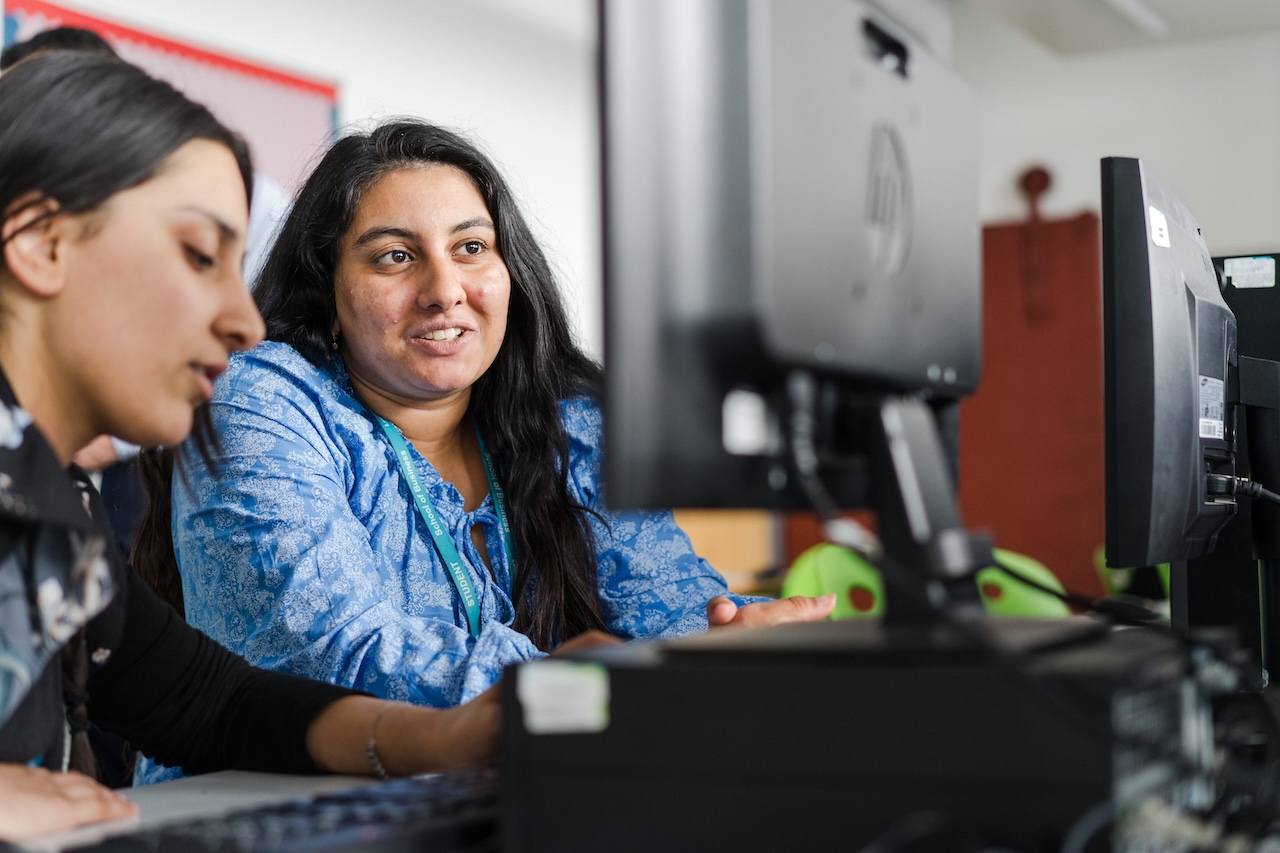 Teacher with student working on a desktop PC