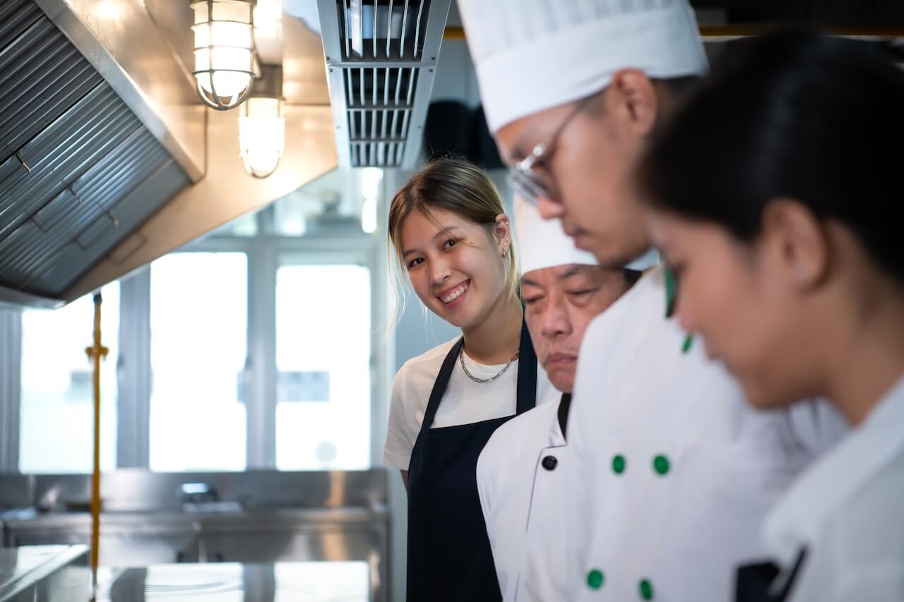Students watching a chef prepare food in the kitchen