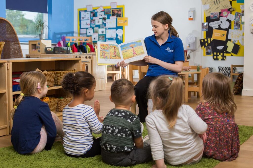 Early years student reading a children's book to a group of young children