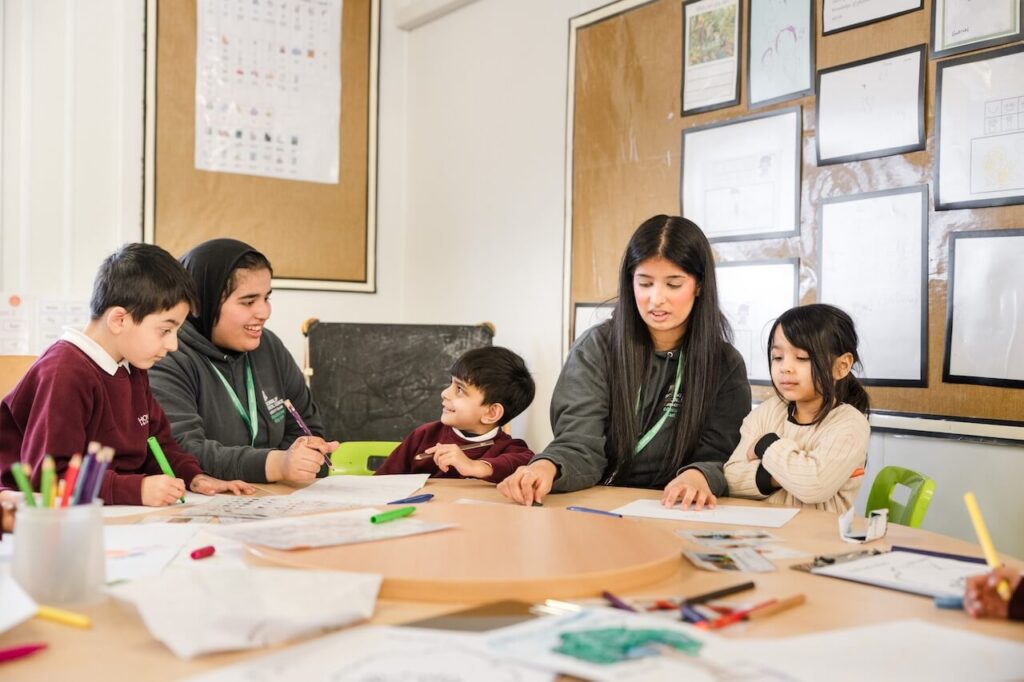 A teacher teaching a class of young children at a table