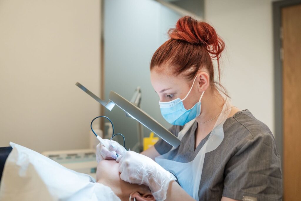 Beauty therapy student wearing a medical mask, working with a hand held electric tool on a client