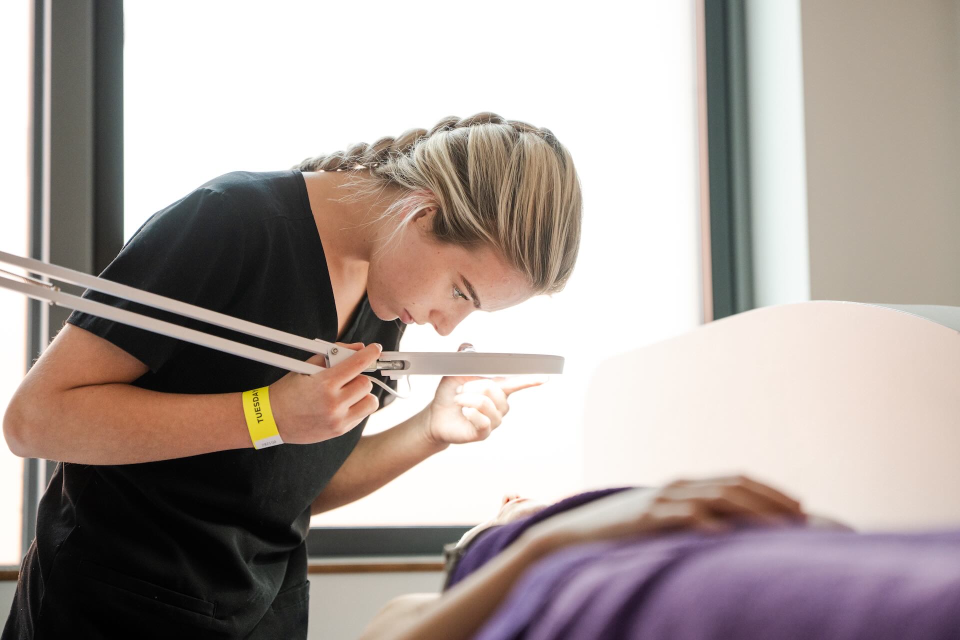 Beauty Therapy Student using a magnifying lens with light to work on a client