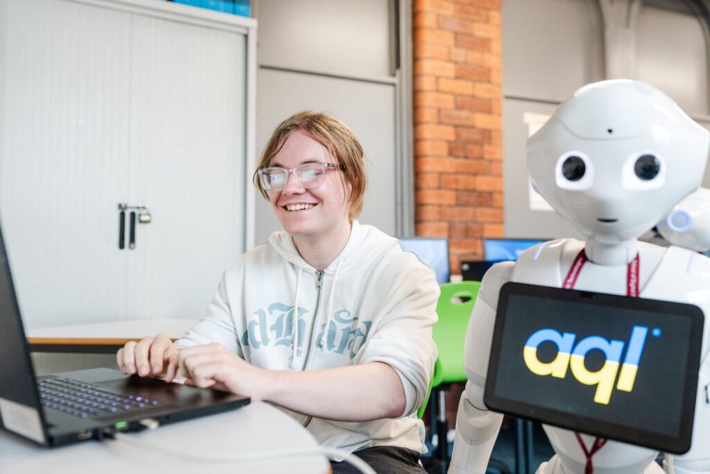 Digital and IT student working on robotics with a large white robot