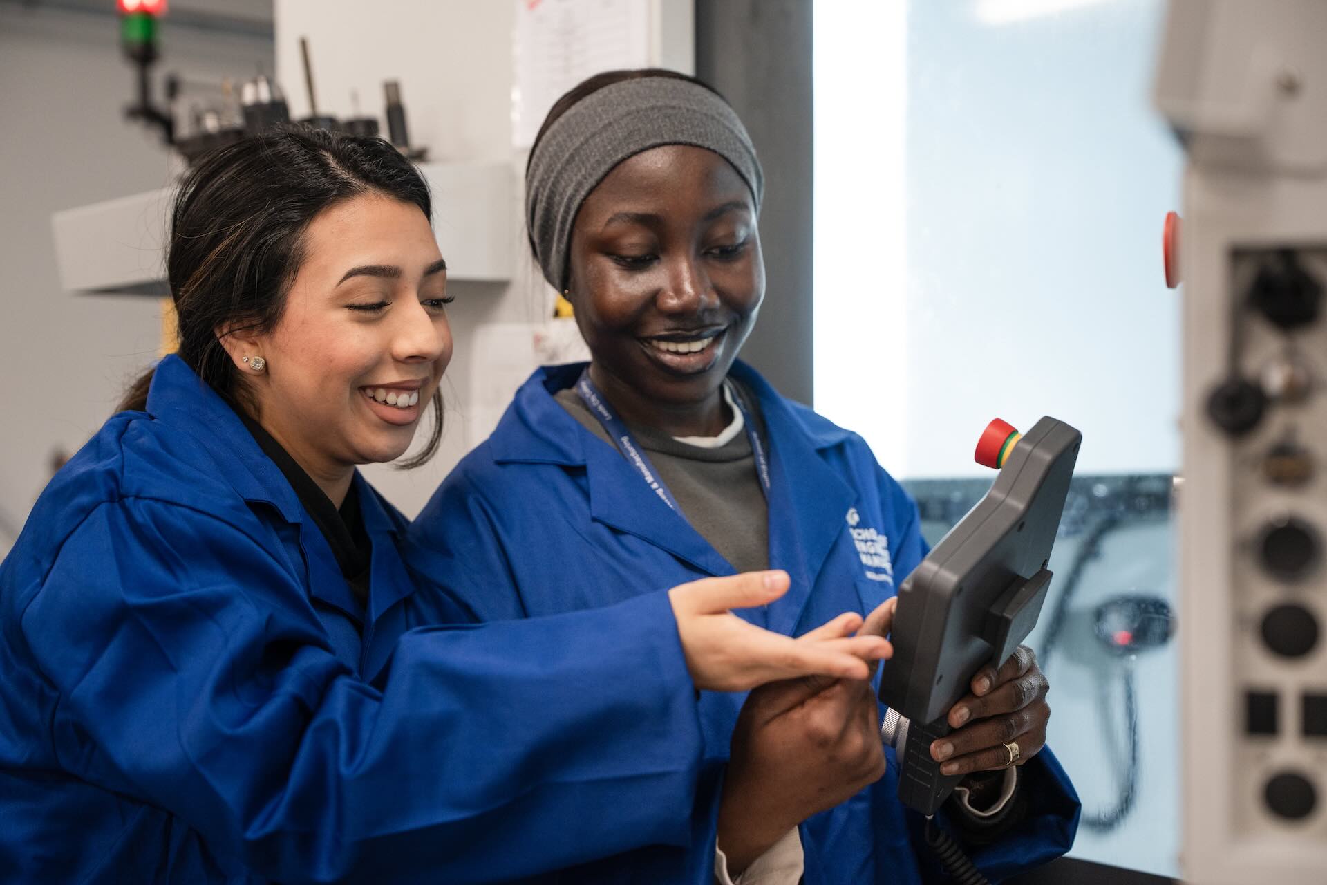 Two Engineering and Manufacturing students holding the controls to operate machinery