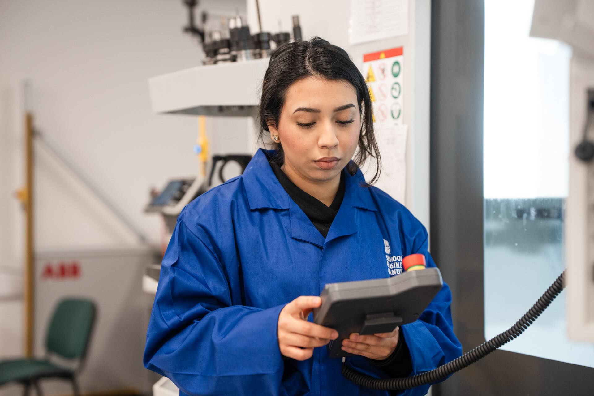 Engineering and Manufacturing student holding the controls to operate machinery