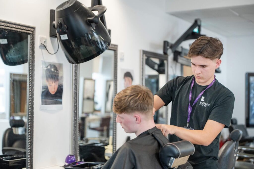 Barber student using a hair clipper to work on a clients hair