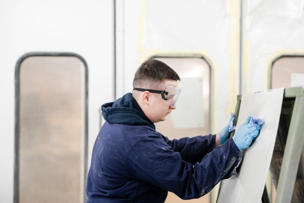 Motor Vehicle student preparing to spray paint a metal sheet