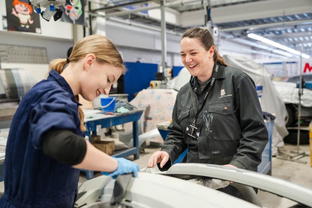 A Motor Vehicle Teacher and student working of the bumpers of a car to get them ready
