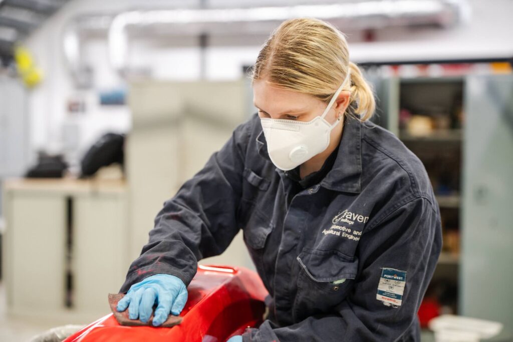 A female Motor Vehicle student doing the top coat of a respray to get it ready for reassembly