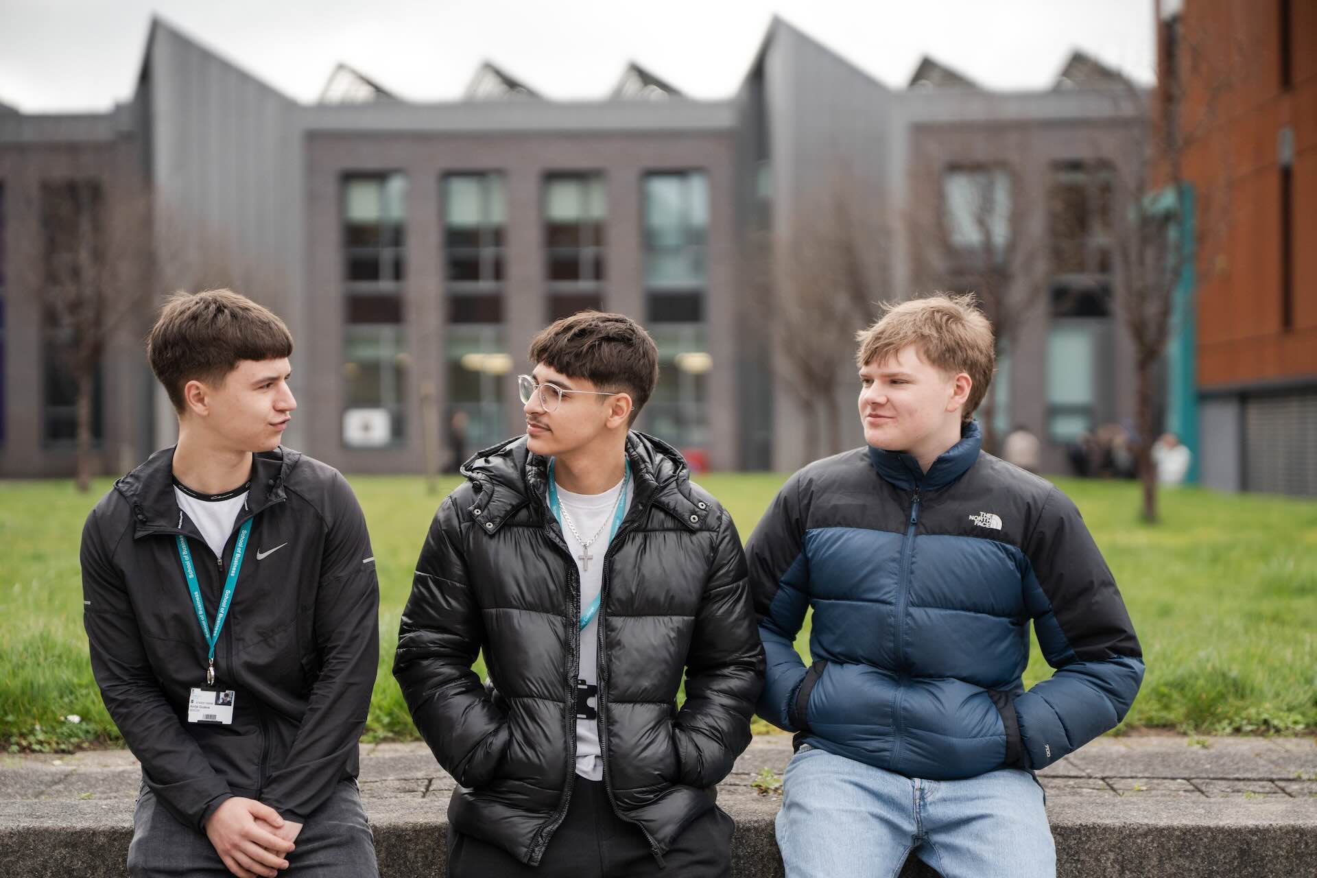 three male students sat outside in the courtyard of PrintWorks