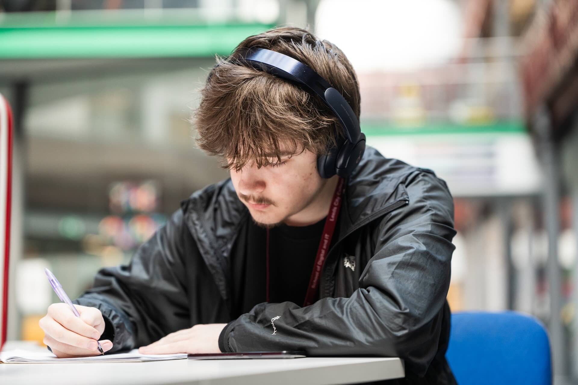 Student wearing headphones and writing notes
