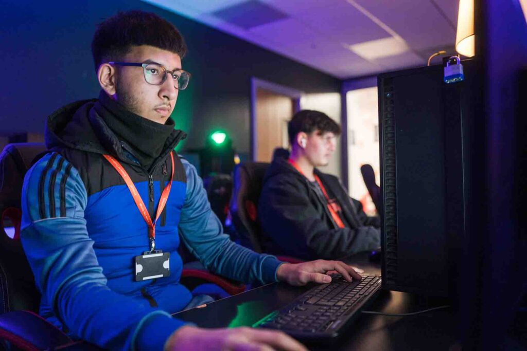 Creative Arts students are sitting in a low-light classroom, totally focused on their computer screens