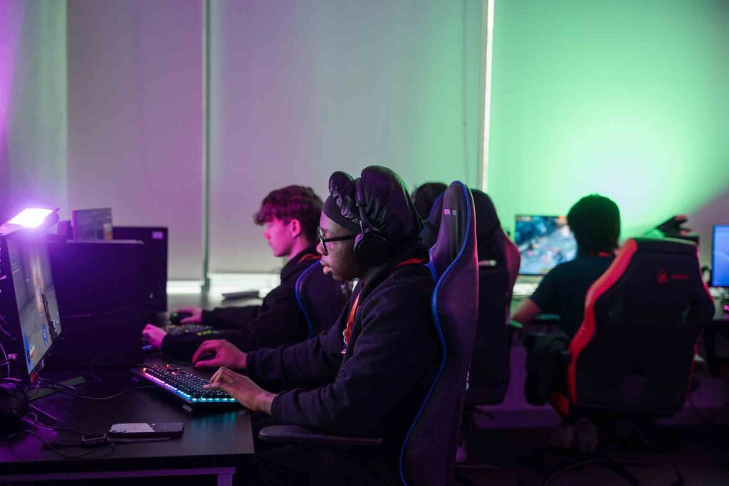 Students in a dimly lit classroom are concentrating and engaging on their computer project