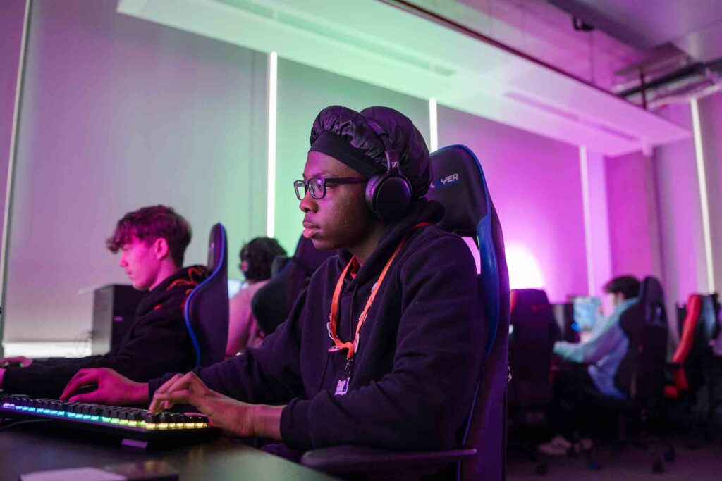 Creative Arts students sitting in gaming chairs, with their cool light-up keyboards glowing in a dimly lit classroom