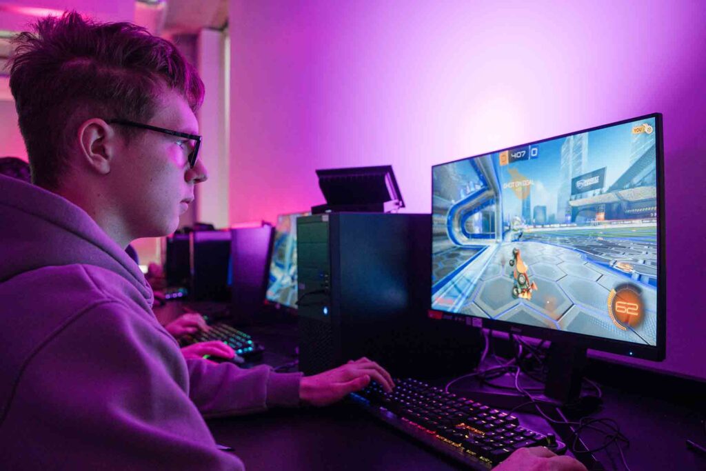 In a softly lit classroom, student wearing a hoodie sitting in front of a computer, captivated by the colourful animations flashing on the screen